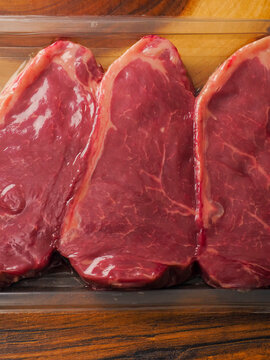 High quality strip loin steaks in a plastic vacuum packed tray. High value beef meat. Preserving and keeping product fresh.