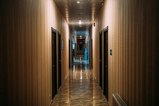 Empty corridor hallway interior architecture hospitality property concept, with closed doors, reflective floor, warm lighting and deep perspective in quiet building.