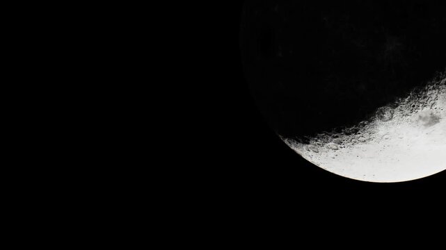 A scene captures the crescent moon in the night sky. The moon is partially illuminated, showing its textured surface with craters. Stars are not visible in this frame.