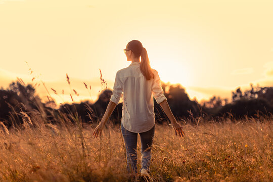 Peaceful Woman Walking Through Golden Meadow at Sunset Enjoying Nature