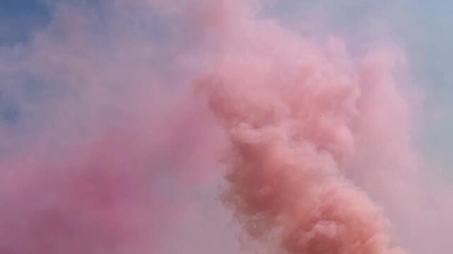 Pink smoke clouds against bright blue sky in conceptual nature imagery