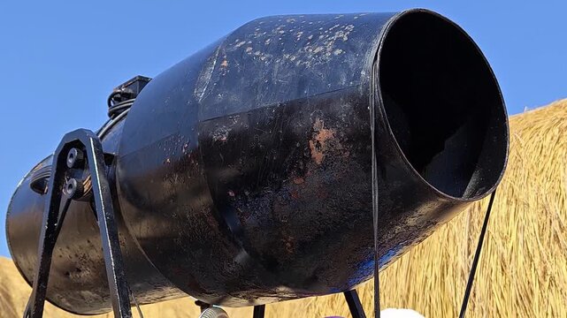 Rusty black cannon against clear blue sky with hay bales