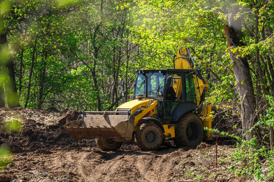 In the forest, the backhoe loader is used to clear areas, build forest roads, and prepare areas for planting trees.