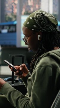 Vertical screen: Woman takes a picture of a boarding pass in a bus terminal while searching the route itinerary online, reviewing bus ticket information on her mobile phone before intercity travel.