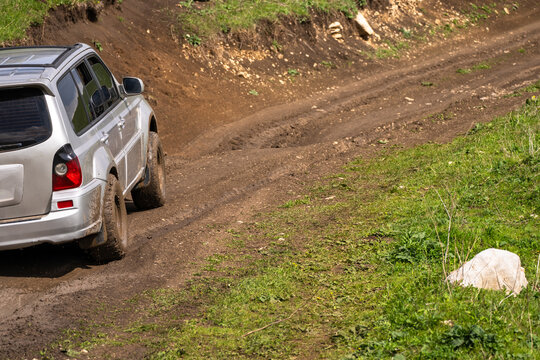 The car drives on a muddy, bad off-road road.