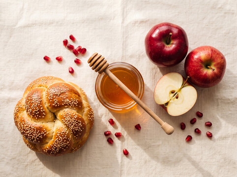 Sweet Rosh Hashanah symbols: challah bread, apples, honey, and pomegranate seeds