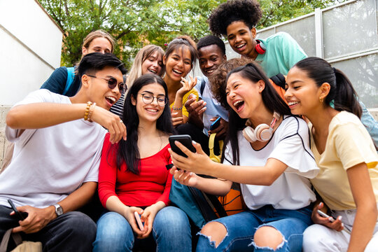 Teenage diverse friends having fun using smartphone outdoors