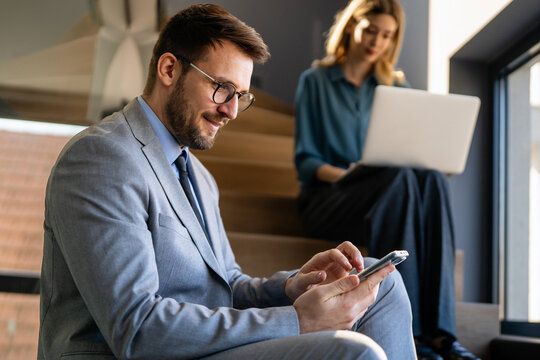 In a modern office, a successful businessman multitasks with phone communication