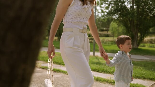 Mother and son walking together hand in hand in the park