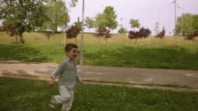 Happy little boy running freely in a city park