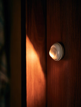 Motion sensor illuminating dark wooden wardrobe interior with warm light, creating responsive smart home atmosphere and crisp shadow transition