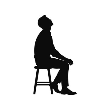 Silhouette of a man sitting on a stool looking up