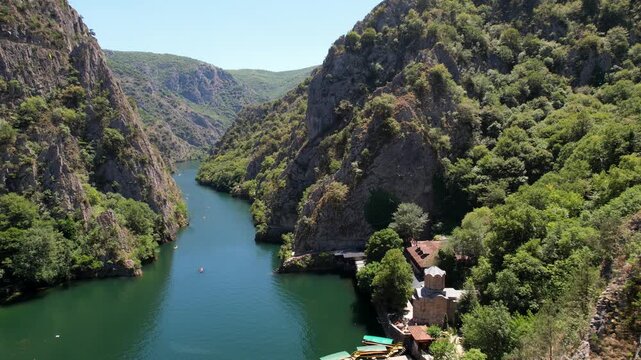 Pier with pleasure boats and church in Matka Canyon Skopje, North Macedonia. Aerial Drone Footage of Boat Journey in Matka Canyon, Skopje, North Macedonia. Aerial panoramic drone view from above, top 