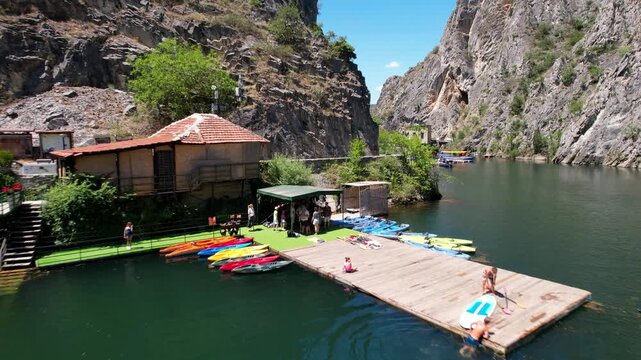 Pier with pleasure boats and church in Matka Canyon Skopje, North Macedonia. Aerial Drone Footage of Boat Journey in Matka Canyon, Skopje, North Macedonia. Aerial panoramic drone view from above, top 