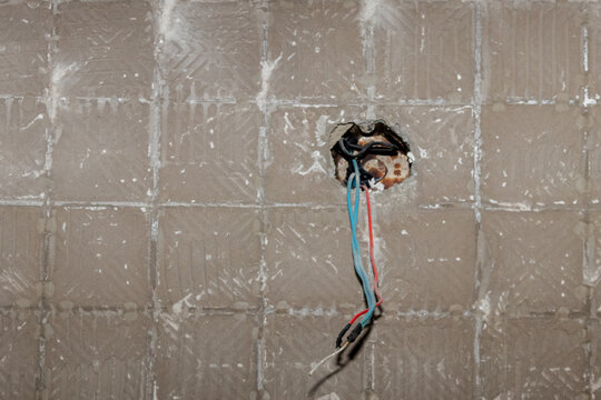 Junction boxes with exposed wiring and hanging colored wires. Focus on home electrical repairs and renovation for stock.