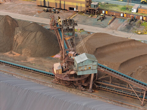 Large Stacker Machine Moving Piles of Coal at an Industrial Mining Site During a Cloudy Afternoon