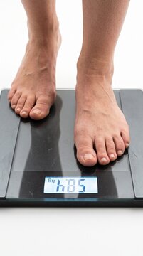 Person's feet on a scale displaying the number 58.5. The person is standing on a digital weight scale to check their body weight.