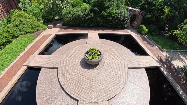 Camera glides above a geometric pond toward Smithsonian Castle in Washington DC.
