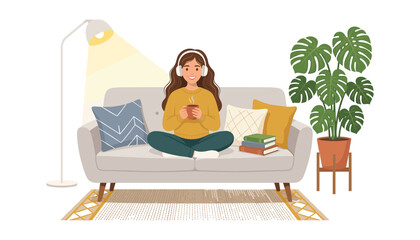 Fototapeta premium Young smiling woman relaxing on a cozy sofa listening to music with headphones and holding a hot beverage