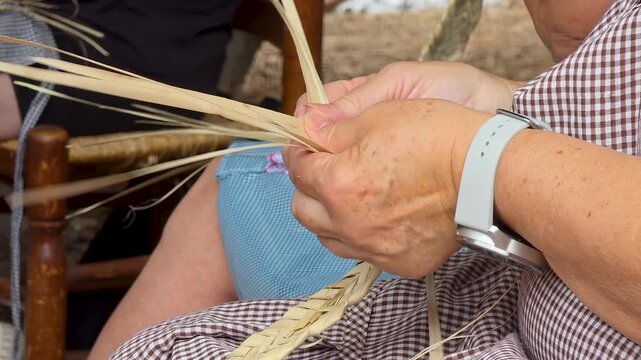 Extreme close up of artisan hands carefully weaving traditional palm leaves llata strips for craft.