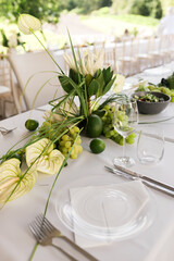 Fototapeta premium Modern Green and White Event Tablescape with Anthurium, Protea, Grapes, Limes and Tropical Foliage, Elegant Botanical Centerpiece and Luxury Outdoor Summer Dining Table Decoration
