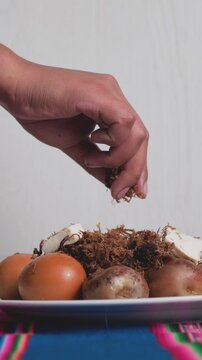 Vertical front view of a Bolivian dish called charquekan, with a woman's hand holding the meat -food concept