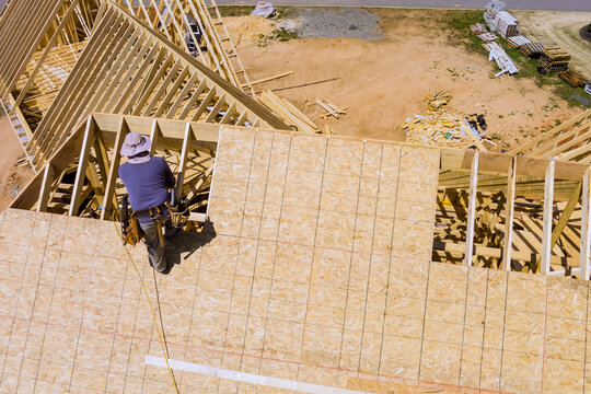 Man stands on top of roof joins frame while working on new building