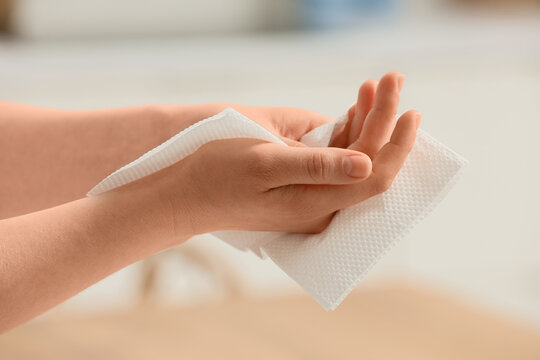 Woman wiping her hands with paper napkin in kitchen, closeup