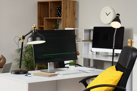 Programmers workplace with computer and lamps in office