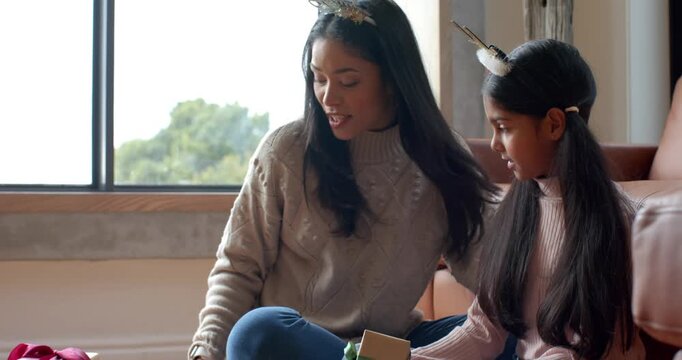 Diverse mom, Indian child at home sharing gift wearing headbands and taking phone pics for Xmas