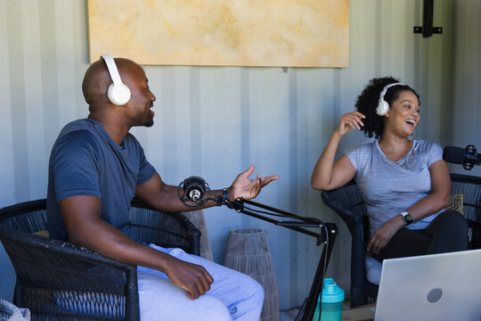 African American co-hosts recording podcast in small studio with microphones, laptop, water bottle
