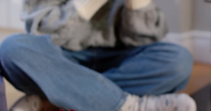 Pullback revealing Asian woman in sweater sitting at home with gifts holding mug sipping for warmth
