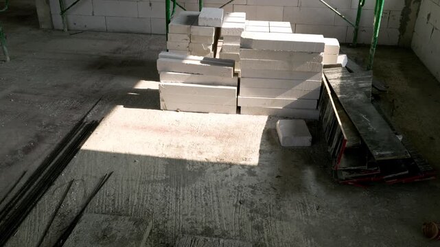 Interior construction site with stacked autoclaved aerated concrete blocks and metal scaffolding.