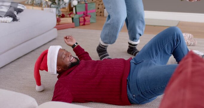Woman is stepping and reaching, pulling child up by arms to help stand near Christmas tree