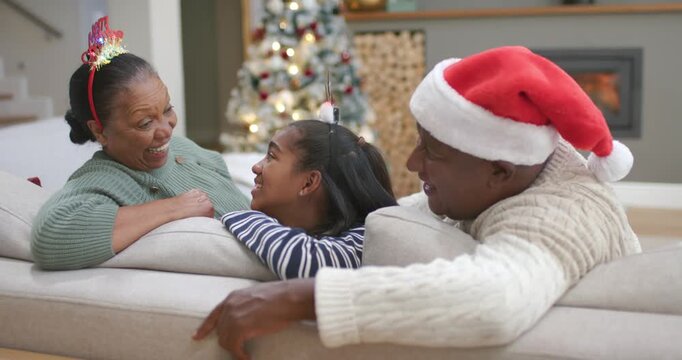 African American family leaning on living room sofa during Xmas, senior giving thumbs-up, laughing