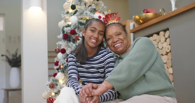 African American senior, youth women holding hands, senior reaching, posing on couch by Xmas tree