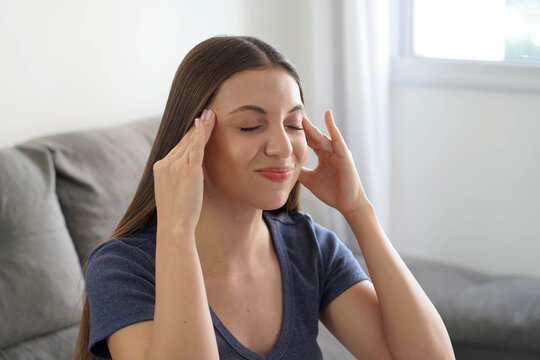 Brazilian woman touching her temples while suffering from painful tension headache at home