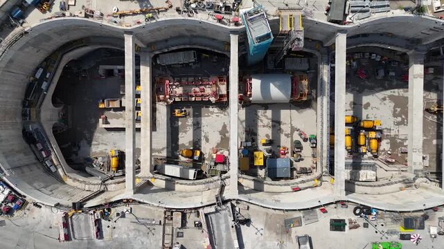 Overhead view of tunnel portals and structural bays inside a deep concrete construction box in west London, with excavators and drilling rigs at work