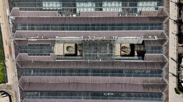 Top down view of the glazed roof of a historic brick warehouse showing rows of skylights and ventilation shafts