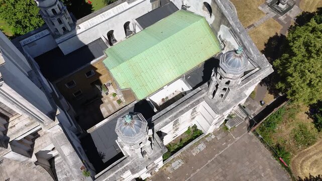 Top down view of a baroque church with a green copper roof, twin turrets and a white stone tower among trees