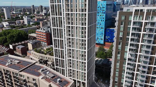 Modern residential towers with white and blue cladding rise above brick apartment blocks and solar panelled roofs in a regenerating district