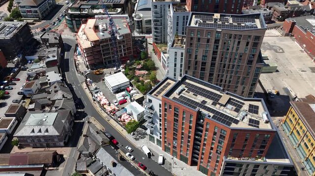 New apartment blocks with solar panelled roofs curve along a street beside a tower crane and ongoing construction work
