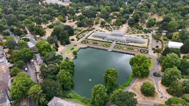Great Victorian palm house and its formal parterre garden stand beside an ornamental lake in botanic gardens