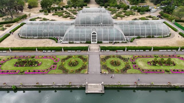 Symmetrical Victorian palm house faces its formal parterre of flower beds across a lake in botanic gardens