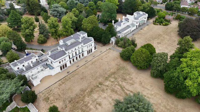 Regency mansion and its neighbouring house look out over parched parkland and mature specimen trees