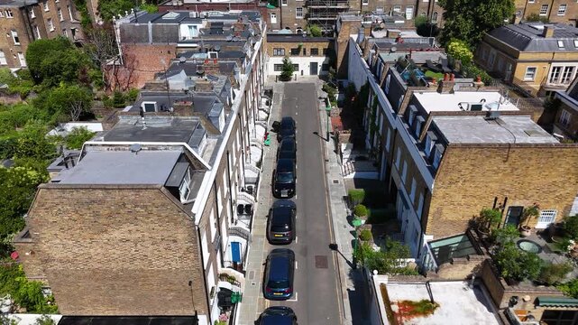 Mews street of brick and painted houses with rooftop gardens and skylights, tucked behind the larger townhouses of a prime district