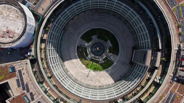 Perfect circle of a ring shaped modernist building with its glazed inner facade and central fountain, seen from directly overhead