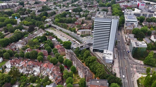 Tall residential tower stands above terraced streets and a busy main road in a leafy west London suburb
