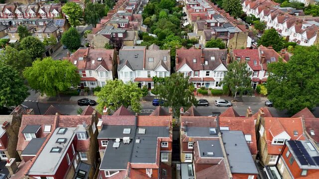 Rows of Edwardian semi detached houses with red tiled roofs, bay windows and long rear gardens line a quiet west London street