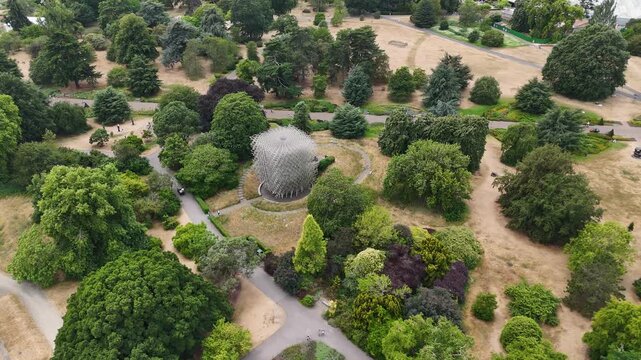 Woven aluminium lattice sculpture stands on parched lawns among specimen trees in botanic gardens